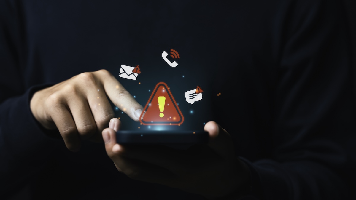 A person is holding a phone that is emitting many warning notifications, including an exclamation mark.