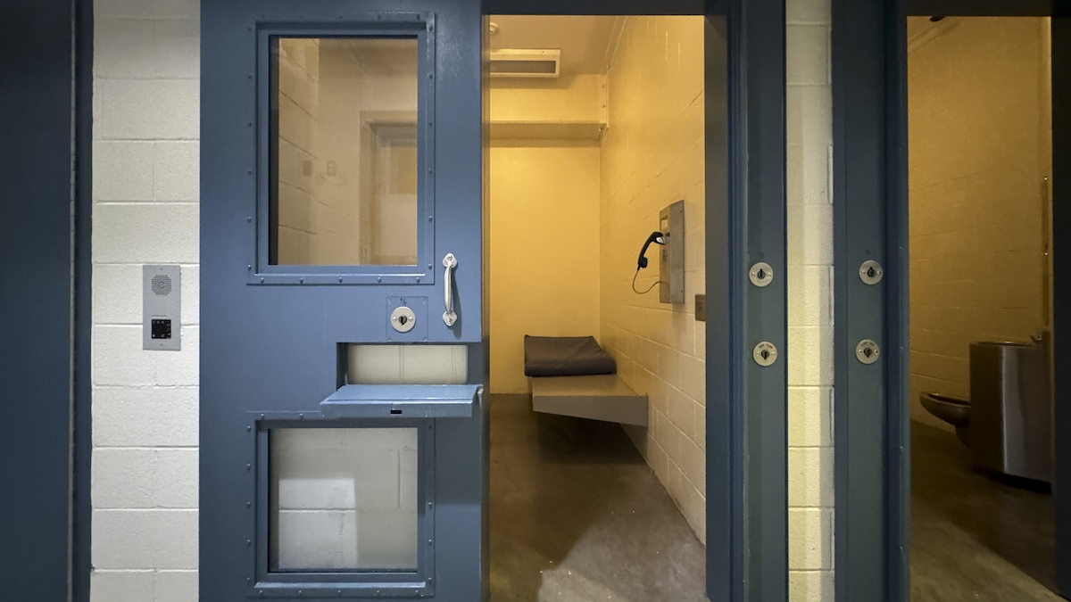 A prison cell with its sliding metal door opened to the left