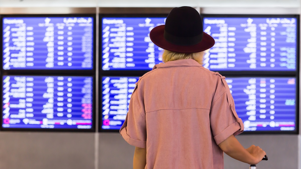 US airline industry quietly selling flight data to DHS A woman stands in front of a timetable that includes information about departing and arriving flights