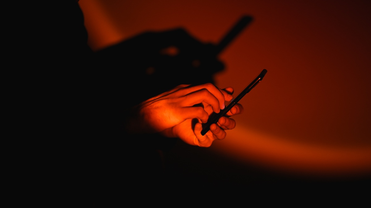 How Google, Adidas, and more were breached in a Salesforce scam A smartphone is held in a person's hand against ominous, orange-red light