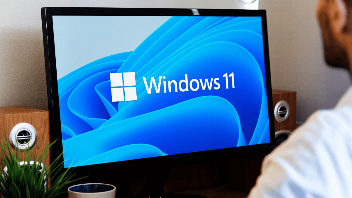A man looking at s Windows 11 logo on a computer screen