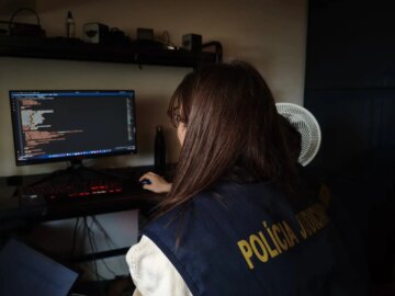 a photo of a European police officer examining a computer at the home of a forum member.