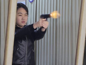 Kim Ju-ae, daughter of North Korean leader Kim Jong-un, test fires a new-type pistol during an inspection of a major munitions factory on Wednesday. Photo: KCNA/EPA